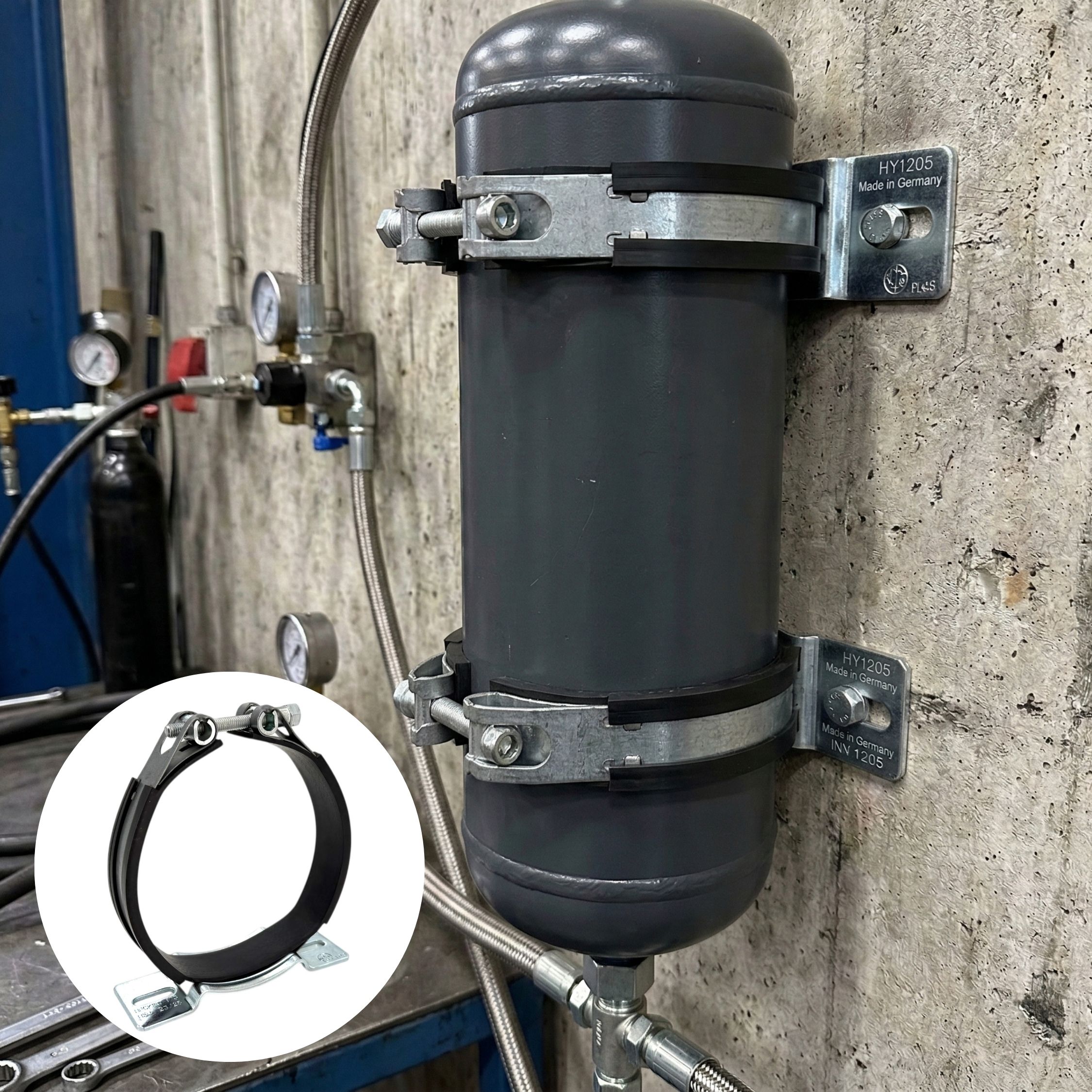 Gelenkbandschelle / Speicherschelle mit Gummierung, Konsole K1: Zwei dieser Schellen befestigen einen grauen Druckbehälter an einer Betonwand; eine einzelne Schelle ist im Detail links unten zu sehen.