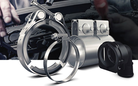 Vielfältige Befestigungselemente: Hochwertige V-Bandschellen, Schlauchschellen und Klemmhalterungen für industrielle Anwendungen. Metall-V-Bandschelle, Schlauchschelle und Kunststoff-Kabelhalterung vor unscharfem Montagehintergrund.