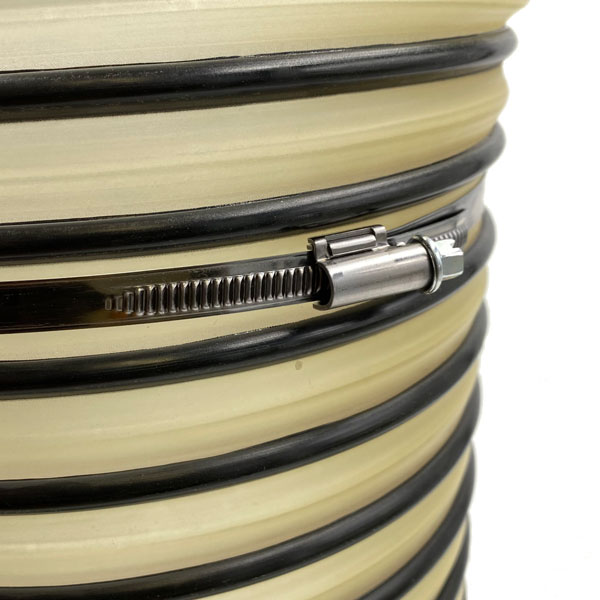 Spiralschlauch mit robuster Metall-Schlauchschelle für sichere Befestigung. Nahaufnahme eines beigen, geriffelten Spiralschlauchs mit schwarzen Ringen, fixiert mit einer glänzenden Metall-Schlauchschelle.