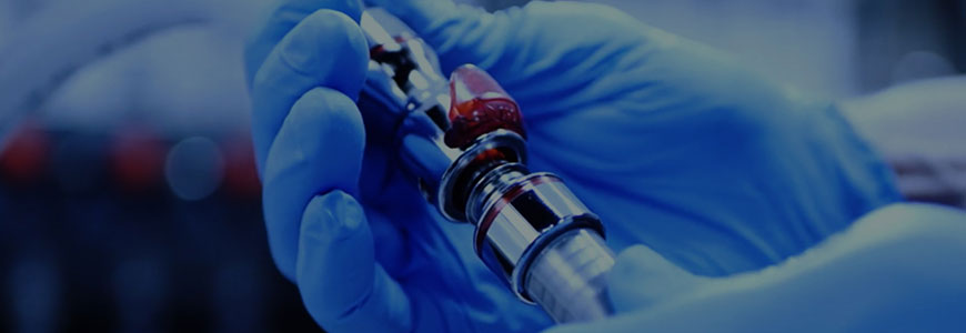 Handhabung eine CPC-Schnellkupplung mit roter Farbcodierung durch eine Person mit blauem Handschuh. Eine in einen blauen Handschuh gekleidete Hand hält ein Schnellkupplung aus Metall mit roter Farbmarkierung