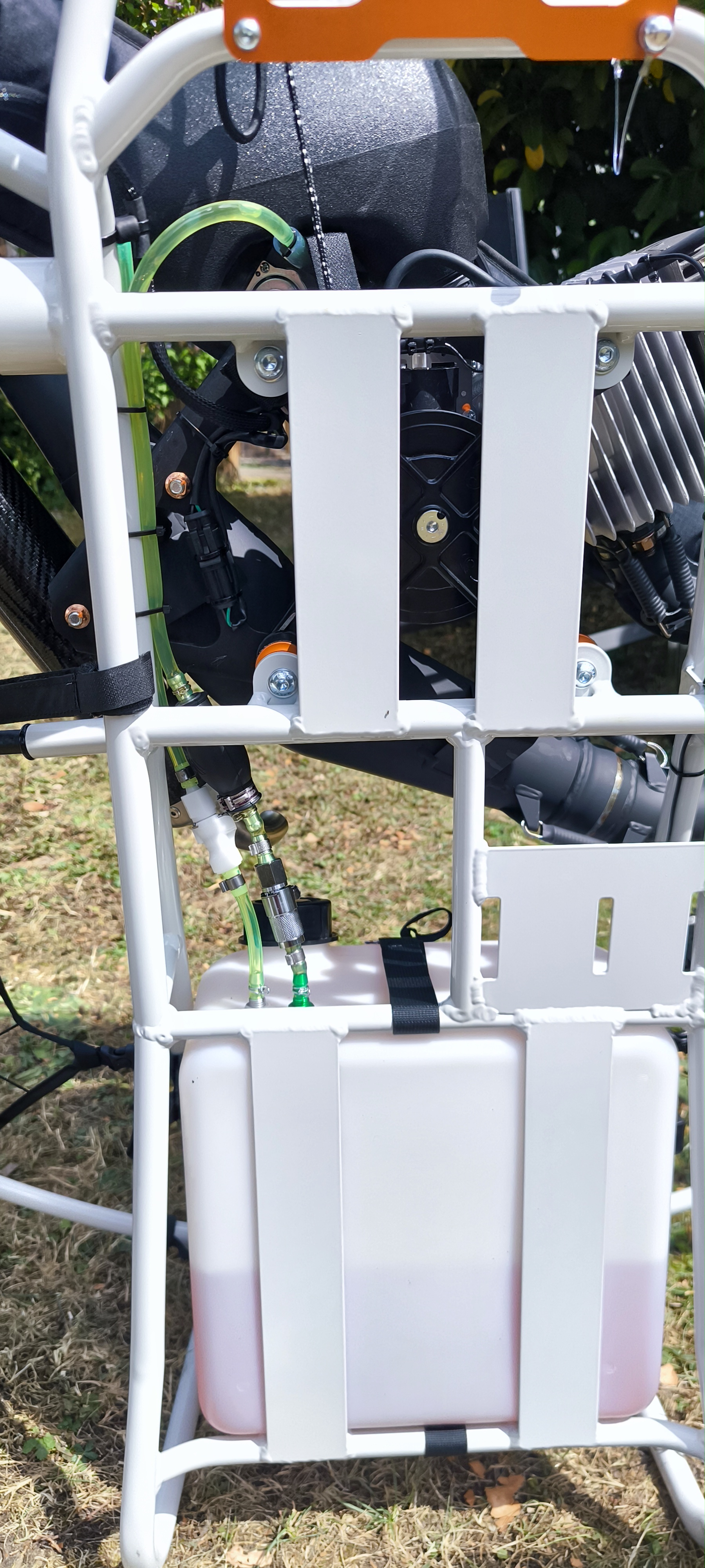 Benzinkupplungen am Paramotor – sicher tanken, sauber transportieren: Detailansicht der transparent grünen Kraftstoffschläuche mit weißen und metallischen Schnellverschlusskupplungen, befestigt am weißen Paramotorrahmen über dem Tank.